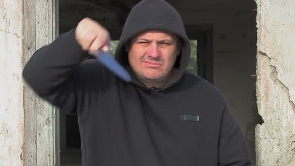 오래 된 건물 근처 야외에서 부엌 칼으로 적극적인 남자 — 비디오