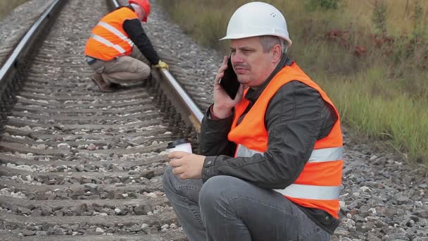 Bahnmitarbeiter telefoniert mit dem Smartphone und trinkt Kaffee — Stockvideo