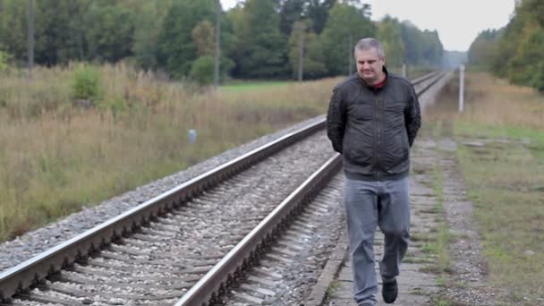 Человек с книгами возле железной дороги — стоковое видео