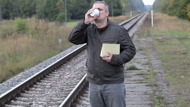 Muž s knihami pití kávy v blízkosti railway — Stock video