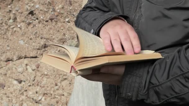 Hombre leyendo libro al aire libre cerca de la pared — Vídeos de Stock