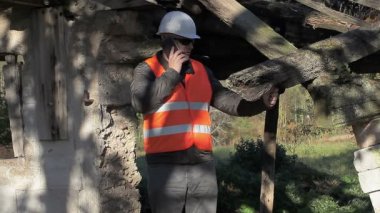 Terk edilmiş yakınındaki smartphone cep telefonu ile konuşurken Müfettiş bina hasarlı bina