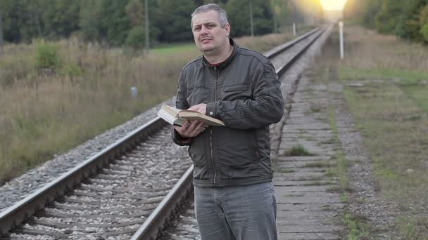 Uomo lettura libro vicino ferrovia — Video Stock