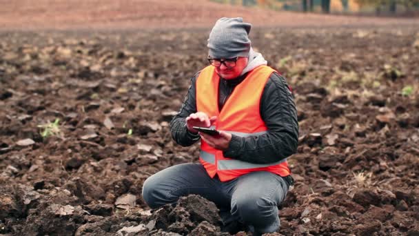 Landwirt kontrolliert Boden auf dem gepflügten Feld — Stockvideo