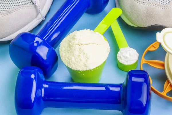 Escovas com proteína de soro de leite puro e creatina com itens esportivos ao redor — Fotografia de Stock