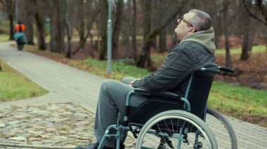 Engelli adam parkta yolda bekleyen tekerlekli sandalyede