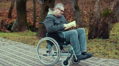 Kitap açık, tekerlekli sandalye ile Engelli adam