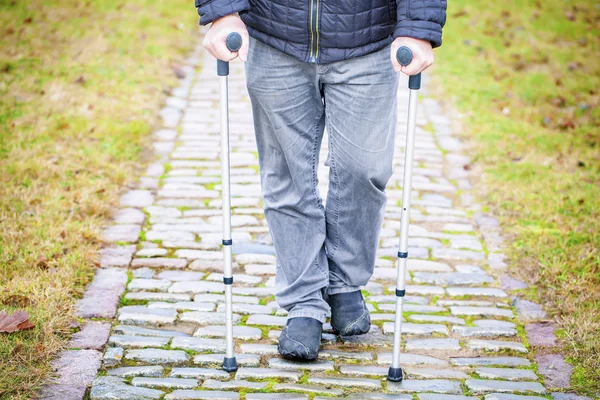 Disabled veteran on crutches at cemetery — Stock Photo, Image