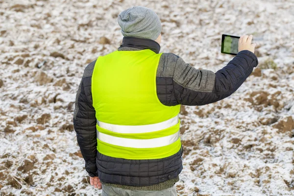 Boer met tablet Pc gefilmd geploegd, bevroren veld met sneeuw — Stockfoto