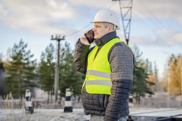 Ingenieur op spoorwegovergang met een smartphone — Stockfoto