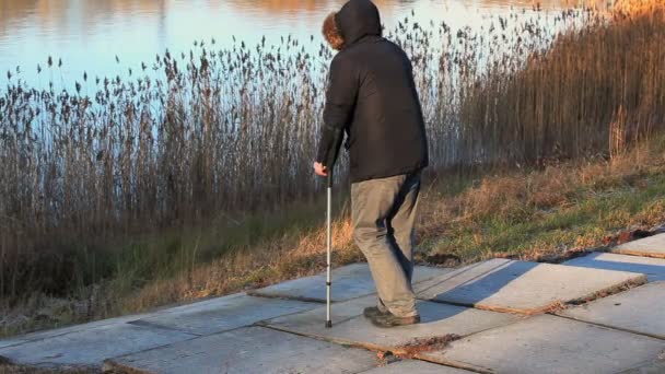 Disabled man on crutches near lake — Stock Video