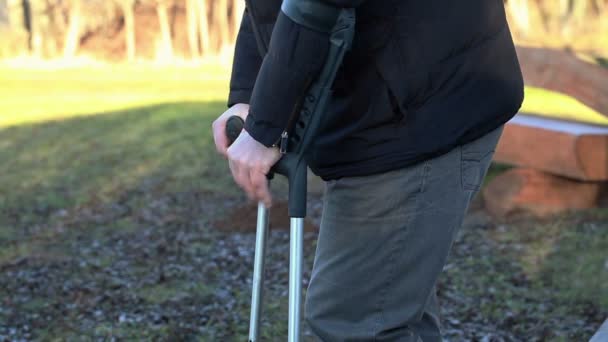 Hombre discapacitado en muletas al aire libre cerca de bancos — Vídeos de Stock