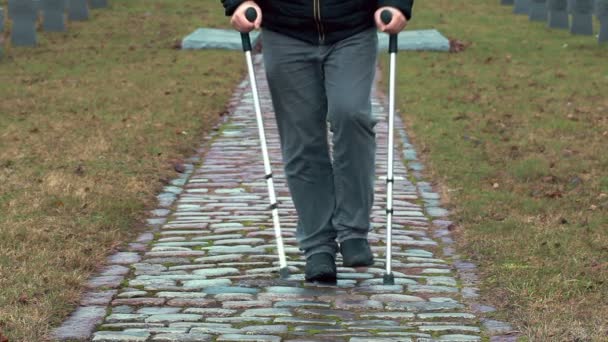 Veterano discapacitado en muletas caminando en el cementerio — Vídeos de Stock