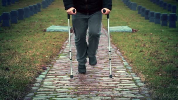 Ancien combattant handicapé sur des béquilles marchant au cimetière — Video