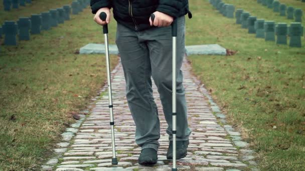 Disabled veteran on crutches walking away at cemetery — Stock Video