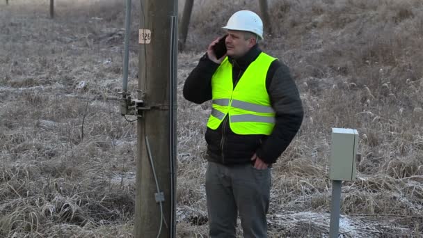 Працівник зі смартфоном на високовольтному стовпі — стокове відео