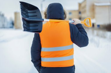 Man with snow shovel near building in winter clipart