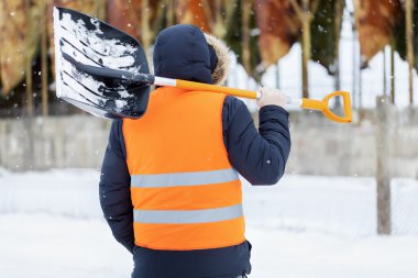 Man with snow shovel near tanks in winter clipart