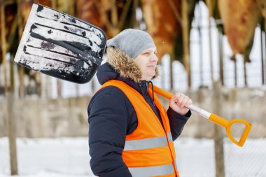 Worker with snow shovel near tanks in winter clipart