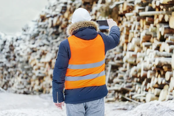 Ingenieur gefilmd stapels van de logs met tablet Pc in de winter — Stockfoto