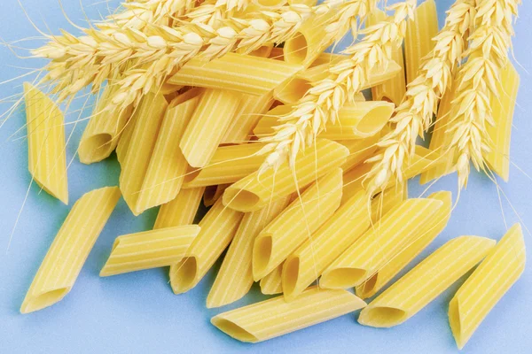 Pasta en oren van tarwe op lichte blauwe achtergrond — Stockfoto