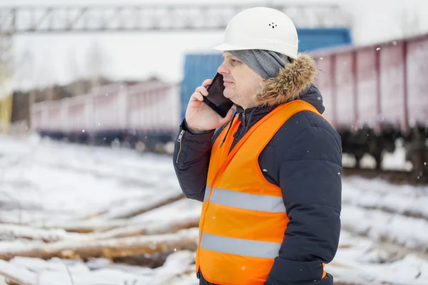 Inżynier mówić na smartphone w pobliżu wagonów towarowych — Zdjęcie stockowe