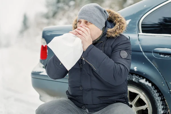Стресовий чоловік вдихає паперовий мішок біля машини на дорозі — стокове фото