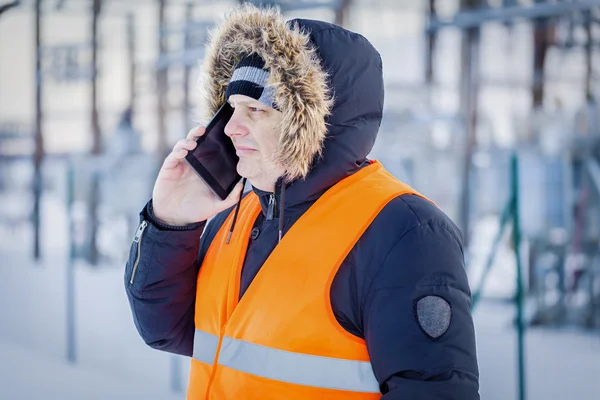 Villanyszerelő, beszél szúró telefon erőmű (télen hólánc) — Stock Fotó