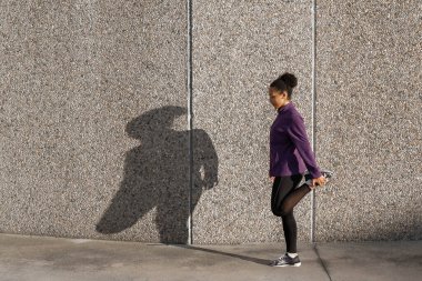 Genç fitness Afrikalı Amerikalı kadın koşucu Önünde bacaklarını açıyor