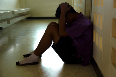 Depresyonda genç bir çocuk yerde oturuyor.