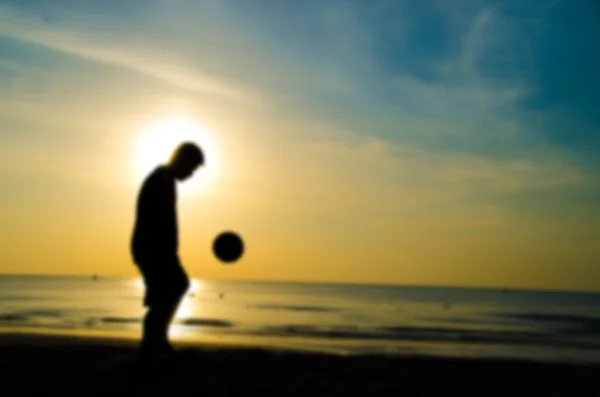 Beachsoccer von der Silhouette des Mannes spielen Fußball am Strand mit verschwommenem Stil — Stockfoto