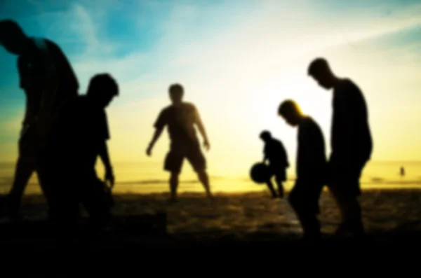 Beachsoccer von der Silhouette des Mannes spielen Fußball am Strand mit verschwommenem Stil — Stockfoto