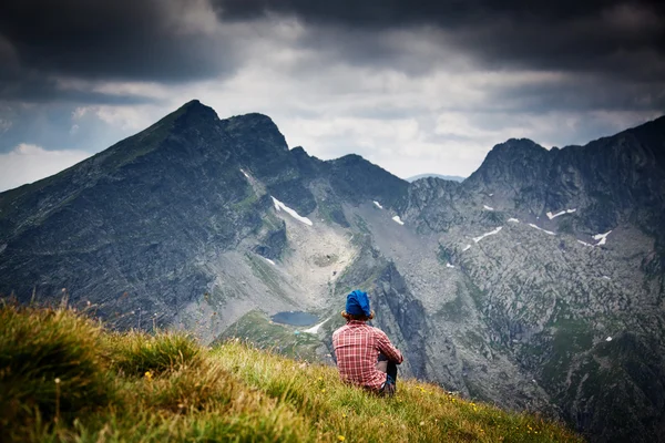 Žena turista relaxační na vrcholu hory obdivování okolní skalnaté vrcholy — Stock fotografie