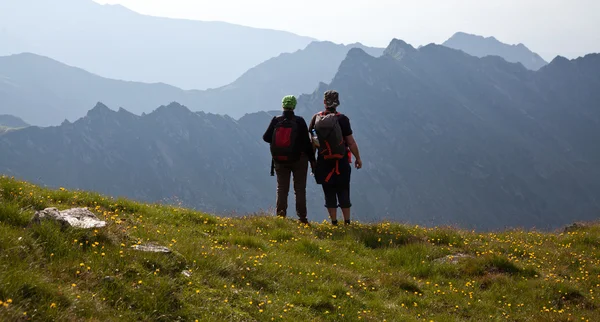 Couple of hikers admiring view and taking photographs of high mountains — Stock Photo, Image