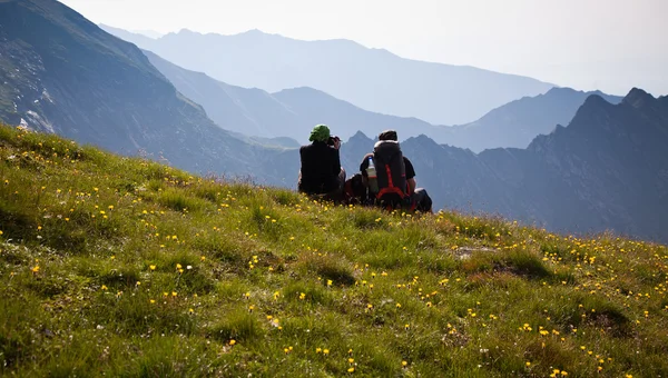 Пара туристов, любующихся видом и фотографирующих высокие горы — стоковое фото
