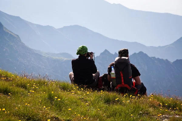 Un paio di escursionisti ammirano la vista e scattano fotografie di alta montagna — Foto Stock