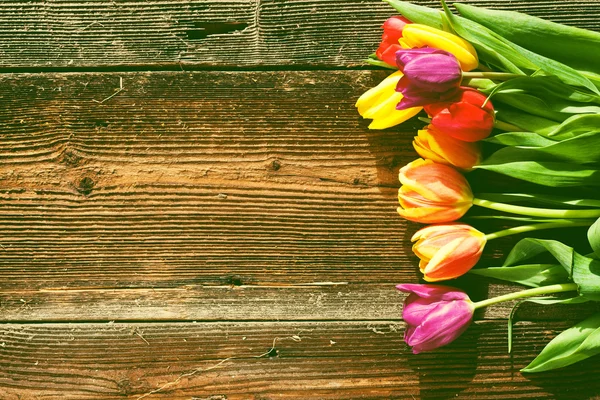 Пасхальні яйця та свіжі весняні тюльпани на обвітреному дерев'яному фоні — стокове фото