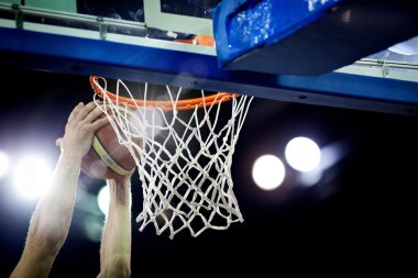 Basketbol bir spor sahasında çemberin içinden geçiyor