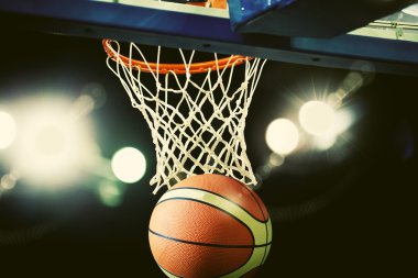 Basketbol bir spor sahasında çemberin içinden geçiyor