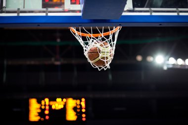 Basketbol bir spor sahasında çemberin içinden geçiyor
