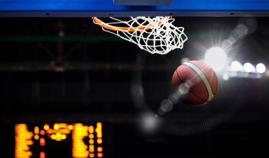 Basketbol bir spor sahasında çemberin içinden geçiyor