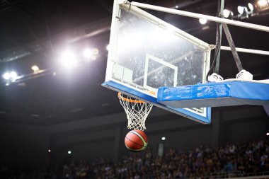 Basketbol bir spor sahasında çemberin içinden geçiyor