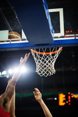 Basketbol bir spor sahasında çemberin içinden geçiyor
