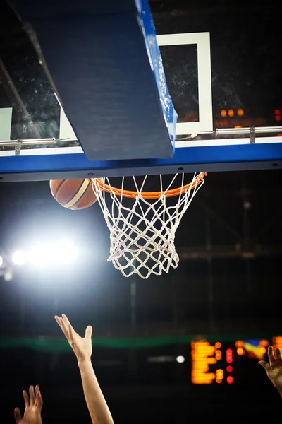 Basquete passando pelo aro em uma arena de esportes — Fotografia de Stock