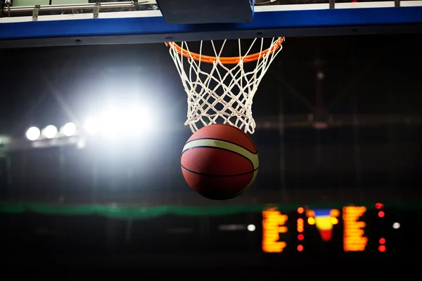 Basquete passando pelo aro em uma arena de esportes — Fotografia de Stock