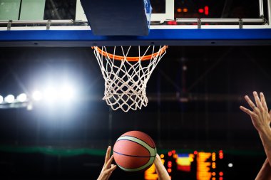 Basketbol bir spor sahasında çemberin içinden geçiyor