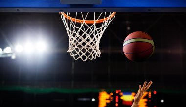 Basketbol bir spor sahasında çemberin içinden geçiyor