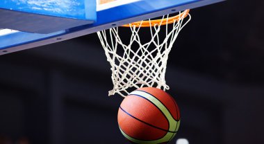 Basketbol bir spor sahasında çemberin içinden geçiyor