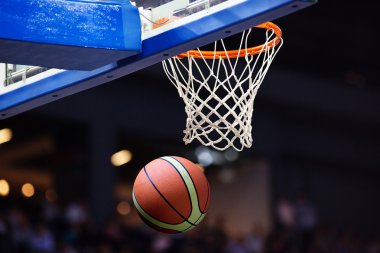 Basketbol bir spor sahasında çemberin içinden geçiyor