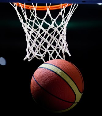 Basketbol bir spor sahasında çemberin içinden geçiyor